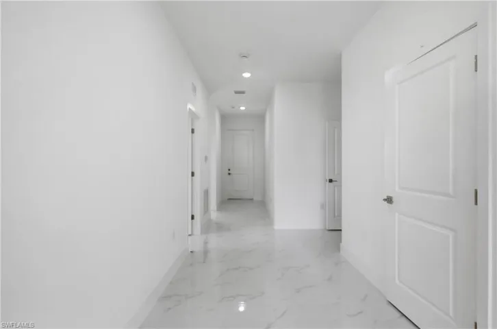 Hallway with recessed lighting and light marble finish floors