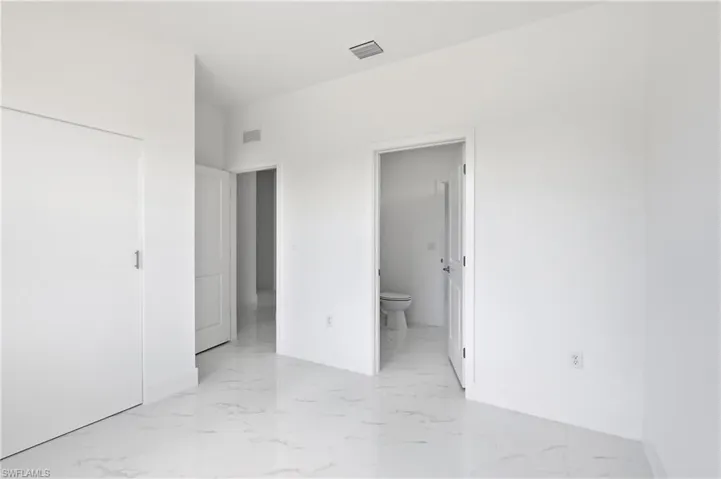 Bedroom with ensuite bath and light marble finish floors