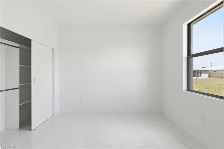 Bedroom featuring light marble finish floors and a closet
