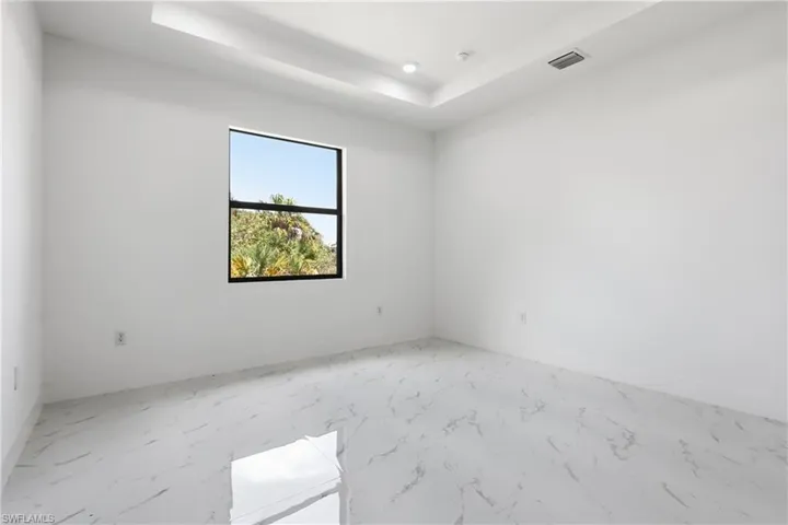 Master Bedroom with a raised ceiling, light marble finish floors, and recessed lighting