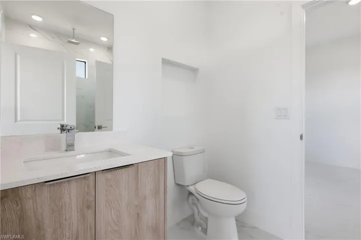 Bathroom featuring light marble finish flooring, vanity, a marble finish shower, and recessed lighting