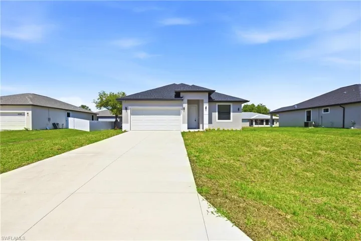 Prairie-style house with a front lawn, driveway, an attached garage, and stucco siding