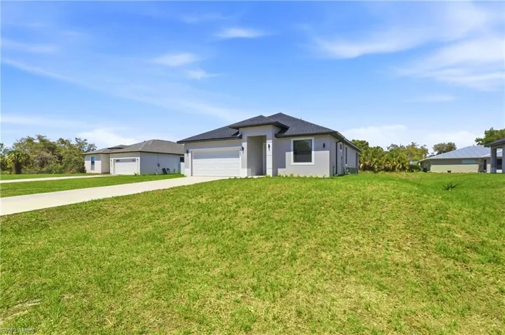 Prairie-style home with driveway, a front yard, an attached garage, and stucco siding