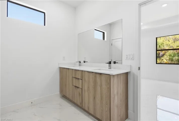 Bathroom featuring double vanity and light marble finish flooring