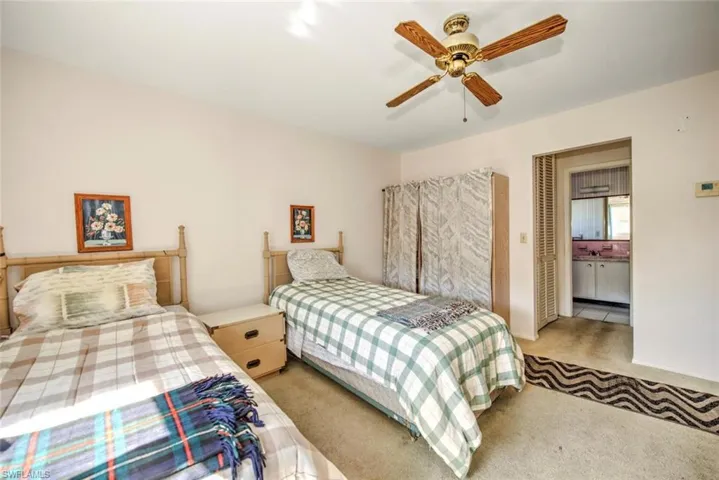 Bedroom featuring light carpet, connected bathroom, and ceiling fan