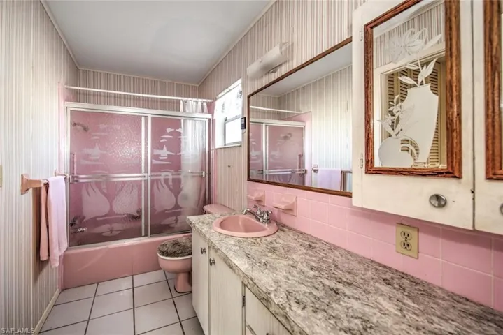 Full bathroom featuring tile patterned flooring, vanity, toilet, and enclosed tub / shower combo