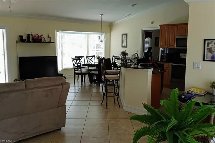 Kitchen featuring stainless steel appliances, light tile patterned flooring, open floor plan, dark countertops, and crown molding