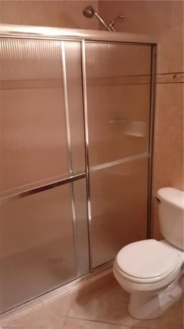 Bathroom featuring tile patterned flooring and a shower with shower door