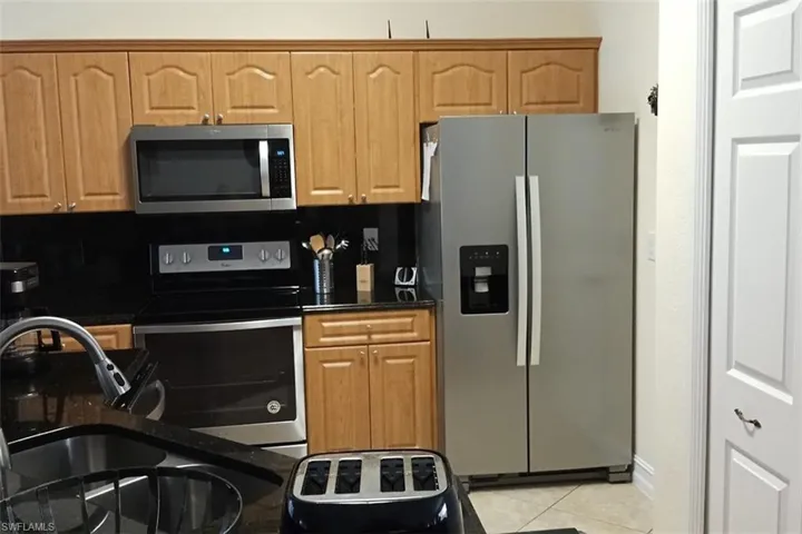 Kitchen featuring stainless steel appliances, light tile patterned floors, and decorative backsplash