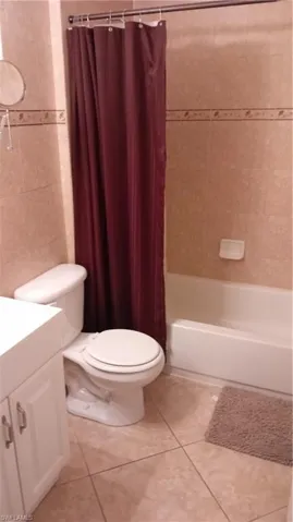 Full bathroom with tile patterned floors, vanity, tile walls, and shower / tub combo