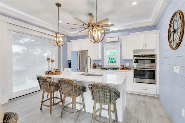 Kitchen featuring hanging light fixtures, light hardwood / wood-style flooring, appliances with stainless steel finishes, a kitchen island with sink, and sink