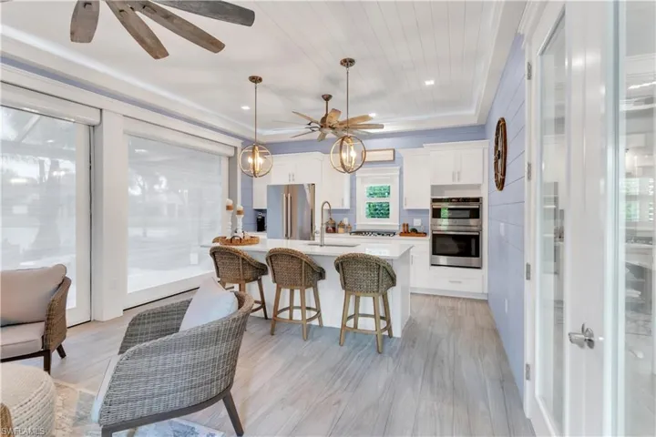 Kitchen with appliances with stainless steel finishes, light hardwood / wood-style floors, hanging light fixtures, and white cabinets