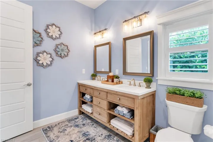 Bathroom featuring double sink vanity, toilet, and hardwood / wood-style floors