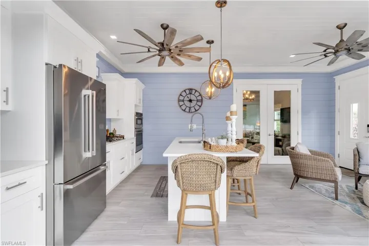 Kitchen with appliances with stainless steel finishes, crown molding, ceiling fan, and decorative light fixtures