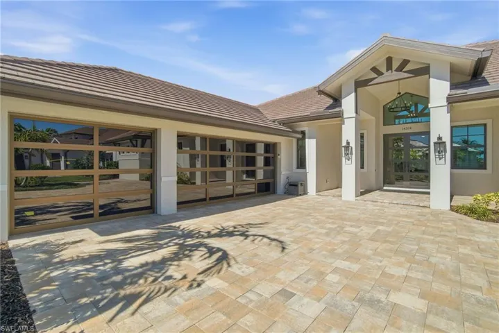 View of exterior entry with french doors, a tiled roof, decorative driveway, and stucco siding