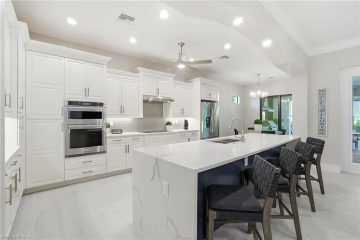 Kitchen featuring a breakfast bar area, decorative light fixtures, appliances with stainless steel finishes, a chandelier, and a ceiling fan