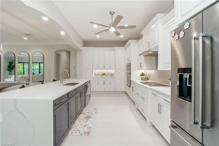 Kitchen featuring appliances with stainless steel finishes, white cabinets, light quartz countertops, under cabinet range hood, and a large island