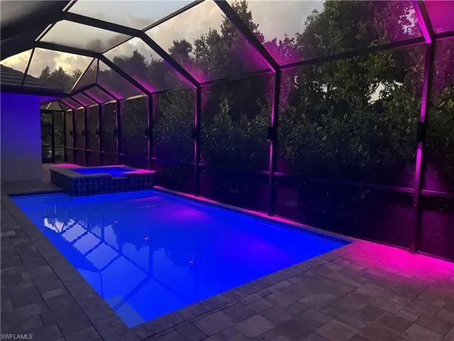 Pool, hot tub and screen enclosure at night with custom lighting