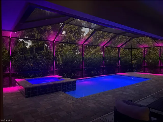 Pool, hot tub and screen enclosure at night with custom lighting