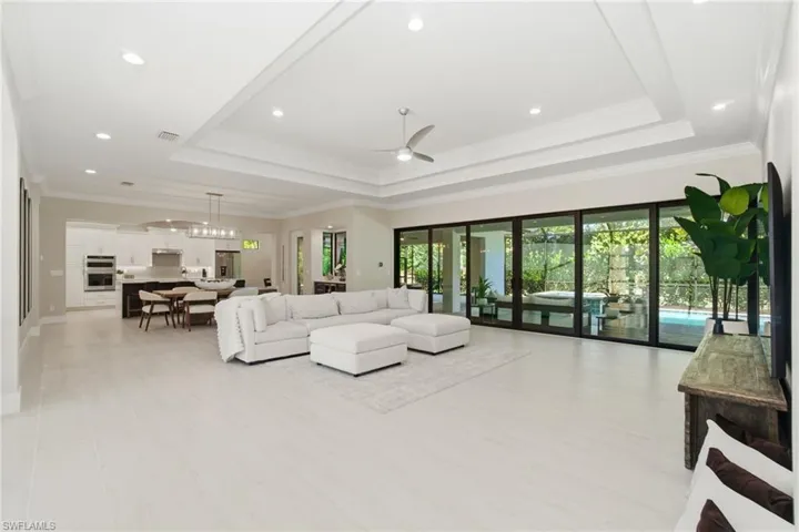 Living room with a tray ceiling, crown molding, a ceiling fan, and recessed lighting