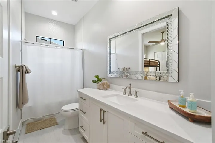 guest bathroom with vanity, shower / tub combo with curtain, and a ceiling fan