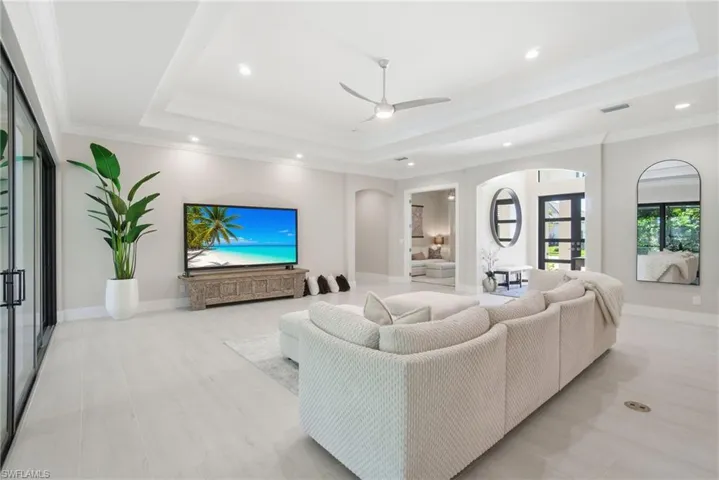 Living area with arched walkways, a ceiling fan, recessed lighting, a tray ceiling