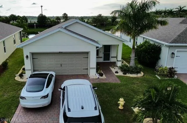 Single story home with decorative driveway, an attached garage, and a front lawn