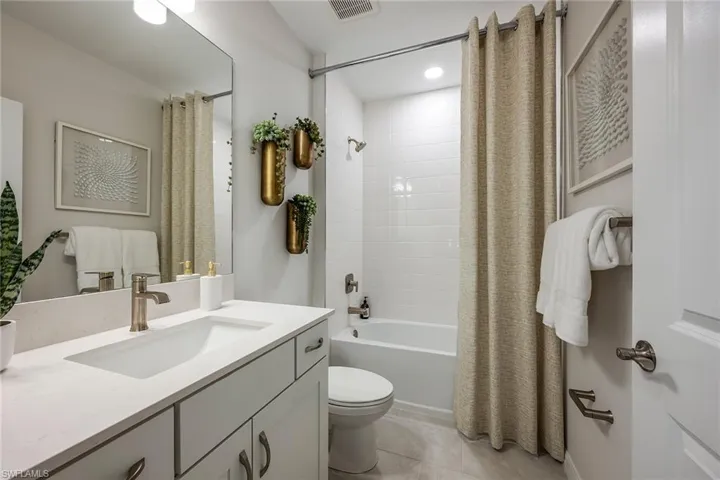 Bathroom with vanity, shower / bathtub combination with curtain, and tile patterned floors