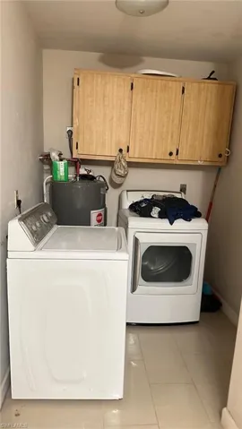 Laundry area featuring light tile patterned floors, washing machine and dryer, and water heater