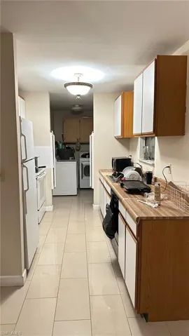Kitchen with brown cabinets, light countertops, light tile patterned flooring, white appliances, and washer / clothes dryer