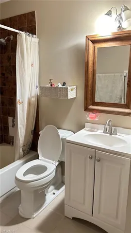 Bathroom featuring shower / bathtub combination with curtain, vanity, and light tile patterned floors