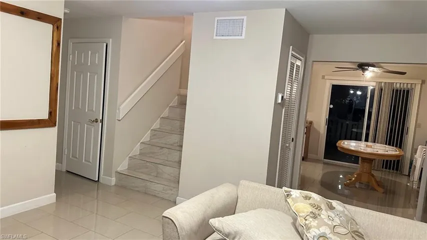 Stairway with tile patterned floors and a ceiling fan