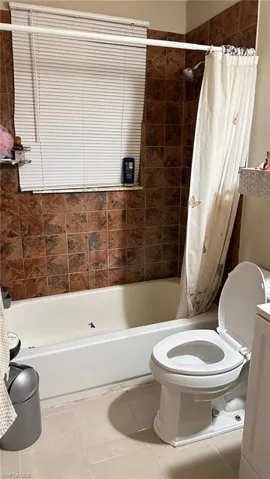 Bathroom featuring shower / tub combo with curtain and tile patterned floors