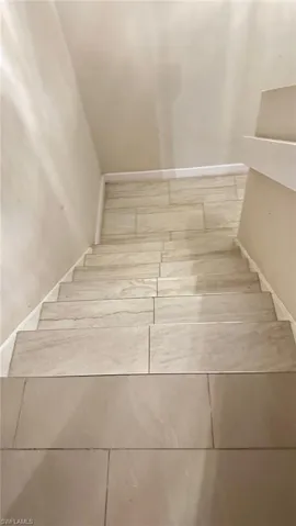 Staircase with tile patterned floors and baseboards