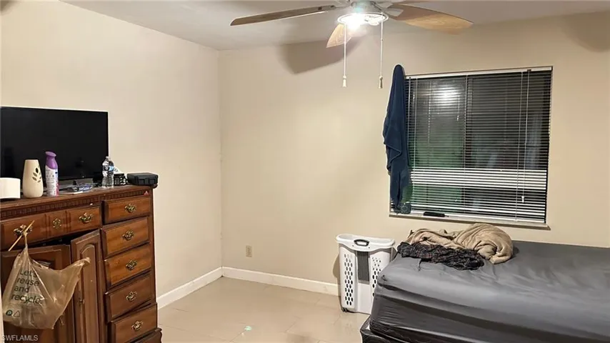 Bedroom with light tile patterned floors and a ceiling fan