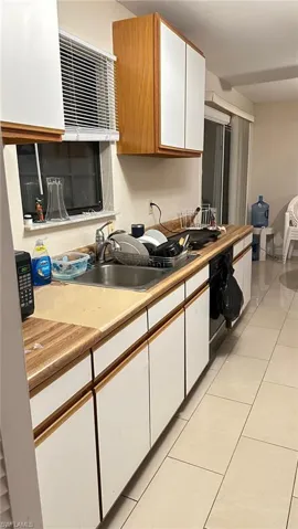 Kitchen featuring white cabinets, brown cabinets, light countertops, light tile patterned floors, and oven