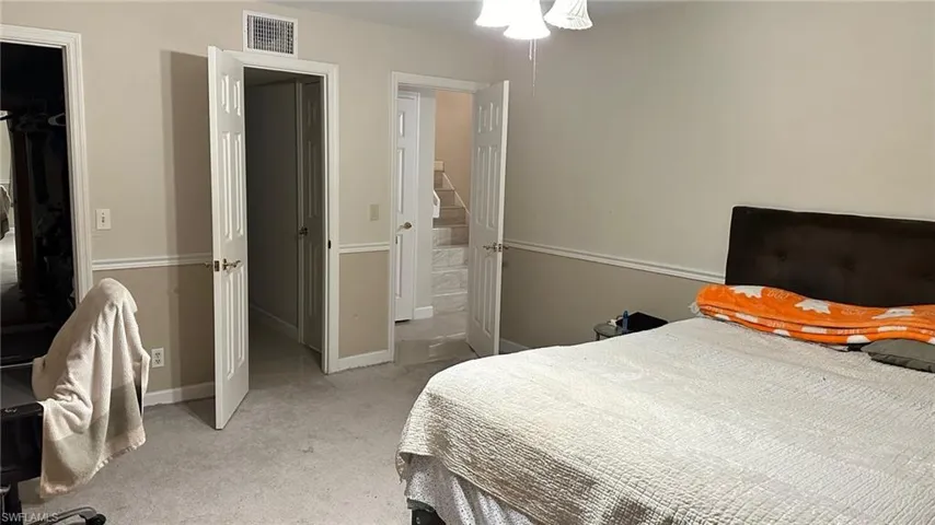 Bedroom with light colored carpet and a spacious closet