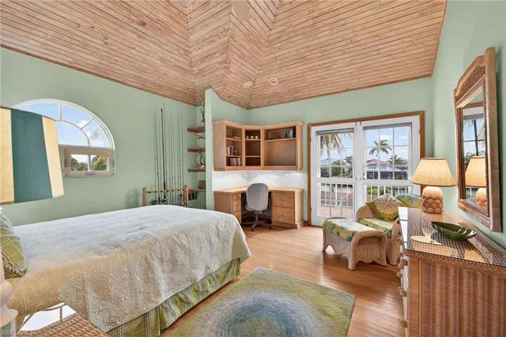 Bedroom with vaulted ceiling, wood ceiling, light wood-type flooring, and built in study area