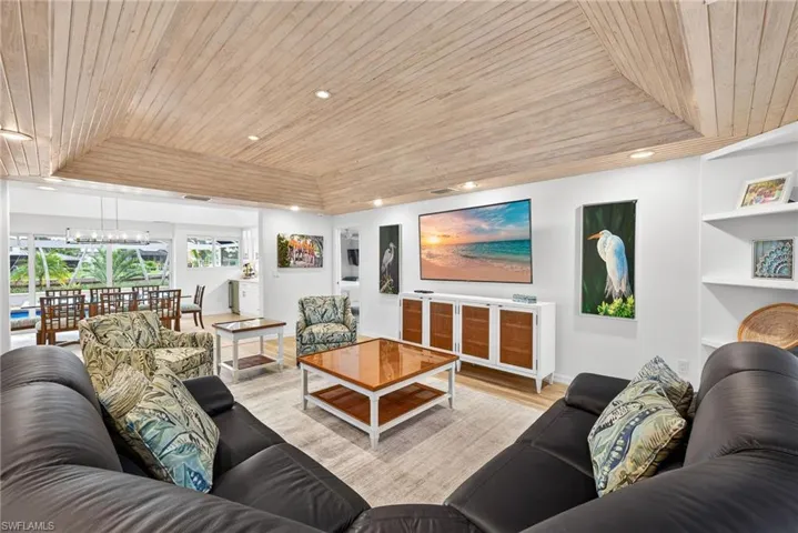 Living room with wood ceiling, a raised ceiling, wood finished floors, and recessed lighting