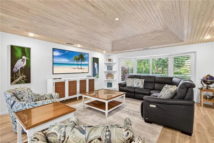Living area featuring wood ceiling, a tray ceiling, light wood-type flooring, built in features, and recessed lighting