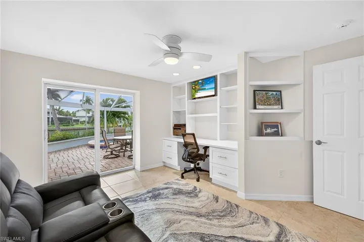 Office featuring ceiling fan, light tile patterned floors, built in study area, and built in shelves