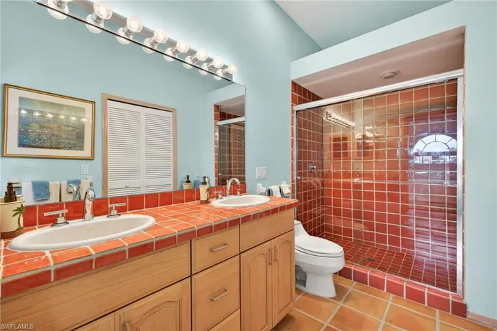 Full bath with double vanity, a shower stall, and light tile patterned flooring