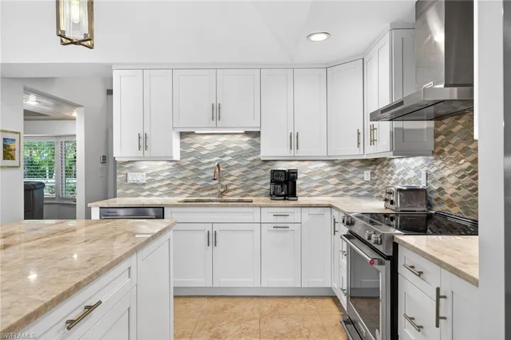 Kitchen featuring stainless steel electric stove, wall chimney exhaust hood, white cabinetry, light stone counters, and recessed lighting