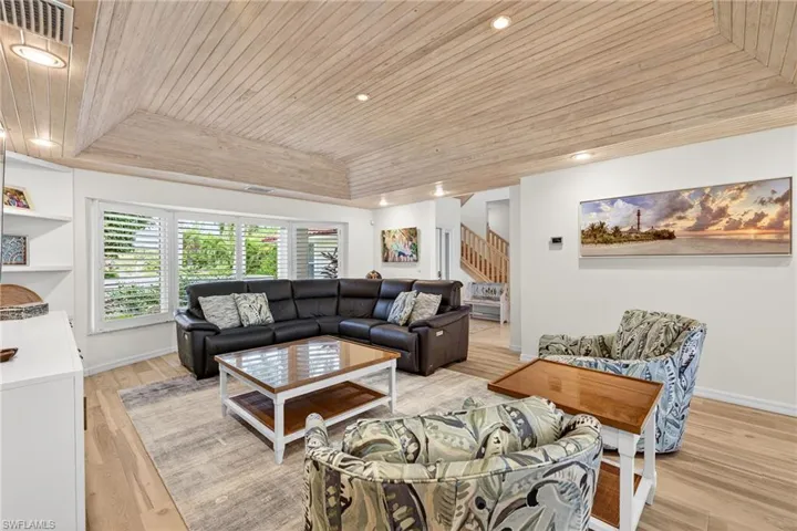 Living area with a tray ceiling, wood ceiling, stairway, light wood finished floors, and recessed lighting