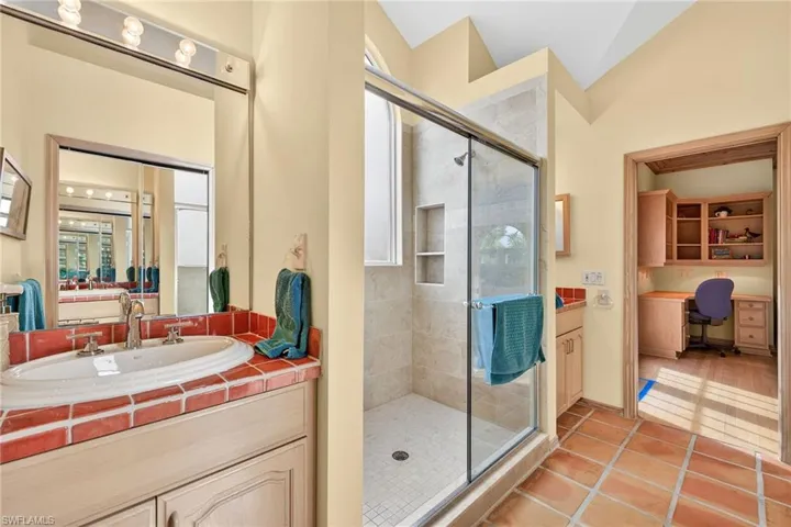 Bathroom with a stall shower, vanity, light tile patterned floors, and vaulted ceiling