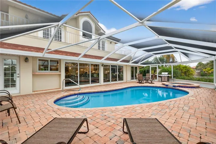 View of swimming pool with a patio area, a sunroom, a grill, and glass enclosure