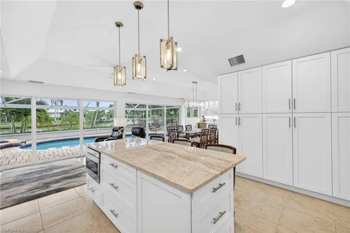 Kitchen featuring white cabinetry, light stone counters, decorative light fixtures, a center island, and recessed lighting