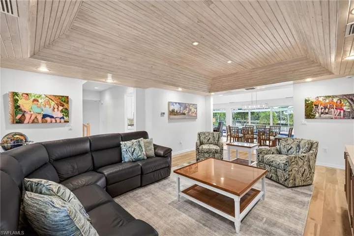 Living room with wooden ceiling, wood finished floors, a tray ceiling, and recessed lighting