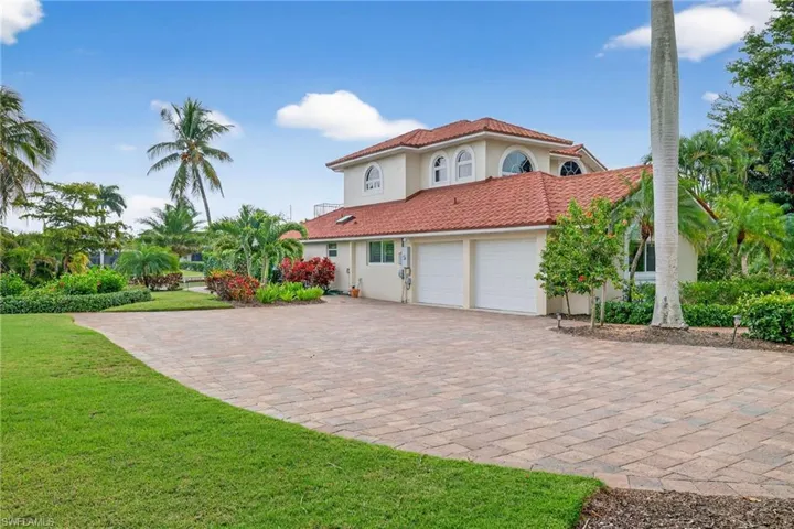 View of front of property with stucco siding, a front lawn, decorative driveway, and a tiled roof