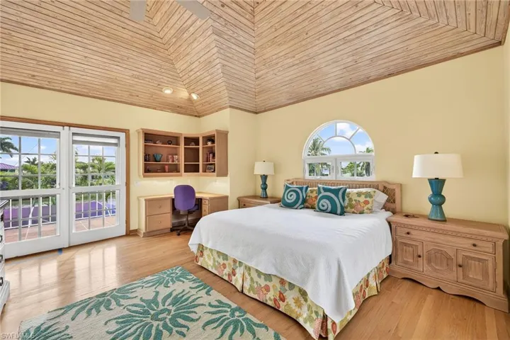 Bedroom featuring wood ceiling, access to outside, vaulted ceiling, built in desk, and multiple windows